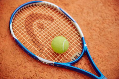 Tenis raketi ve açık havada renkli bir sahada top.