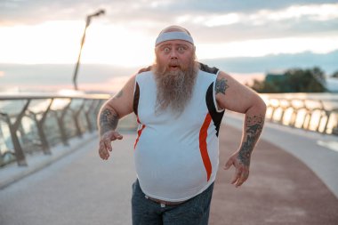 Şişman, beyaz sakallı ve cesur adam sabah egzersizleri yapıyor.