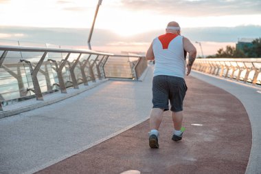 Şişman, beyaz sakallı ve cesur adam sabah egzersizleri yapıyor.