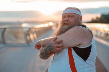 Şişman, beyaz sakallı ve cesur adam sabah egzersizleri yapıyor.