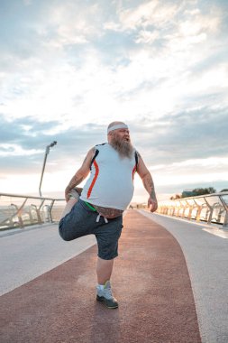 Şişman, beyaz sakallı ve cesur adam sabah egzersizleri yapıyor.