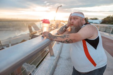 Şişman, beyaz sakallı ve cesur adam sabah egzersizleri yapıyor.