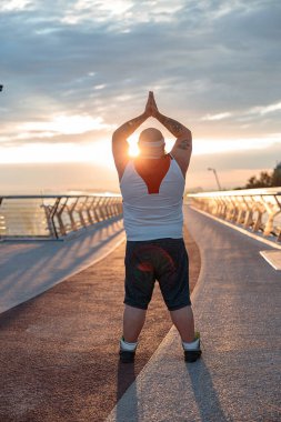 Şişman, beyaz sakallı ve cesur adam sabah egzersizleri yapıyor.