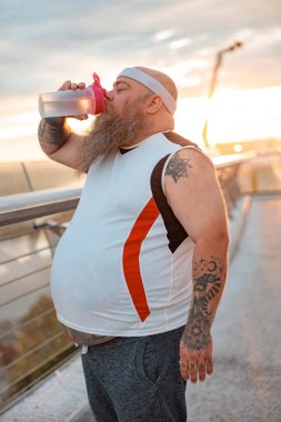 Şişman, beyaz sakallı ve cesur adam sabah egzersizleri yapıyor.