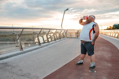 Şişman, beyaz sakallı ve cesur adam sabah egzersizleri yapıyor.