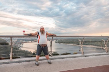 Şişman, beyaz sakallı ve cesur adam sabah egzersizleri yapıyor.