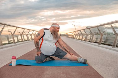 Şişman, beyaz sakallı ve cesur adam sabah egzersizleri yapıyor.