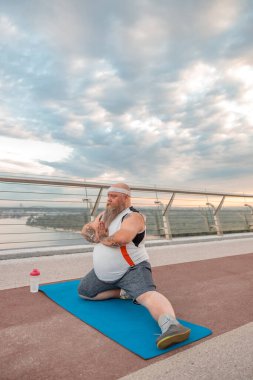 Şişman, beyaz sakallı ve cesur adam sabah egzersizleri yapıyor.