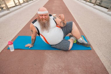 Şişman, beyaz sakallı ve cesur adam sabah egzersizleri yapıyor.