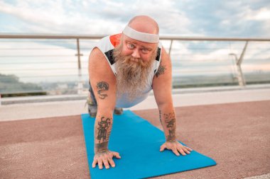 Şişman, beyaz sakallı ve cesur adam sabah egzersizleri yapıyor.