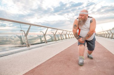 Şişman, beyaz sakallı ve cesur adam sabah egzersizleri yapıyor.