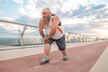 Şişman, beyaz sakallı ve cesur adam sabah egzersizleri yapıyor.