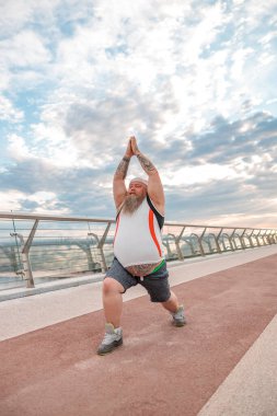 Şişman, beyaz sakallı ve cesur adam sabah egzersizleri yapıyor.