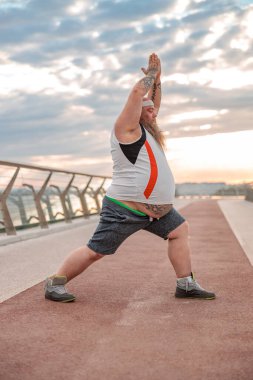 Şişman, beyaz sakallı ve cesur adam sabah egzersizleri yapıyor.