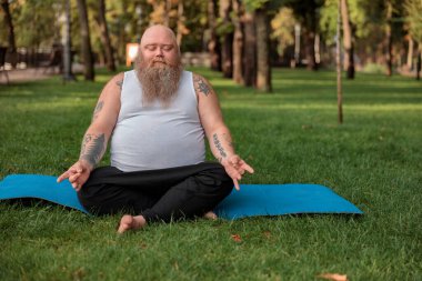 Şişman, beyaz sakallı ve cesur adam sabah egzersizleri yapıyor.