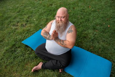 Şişman, beyaz sakallı ve cesur adam sabah egzersizleri yapıyor.