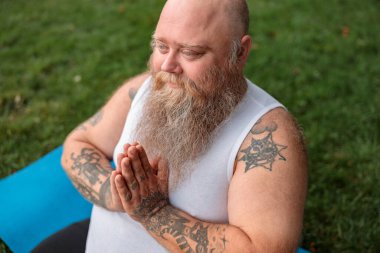 Şişman, beyaz sakallı ve cesur adam sabah egzersizleri yapıyor.