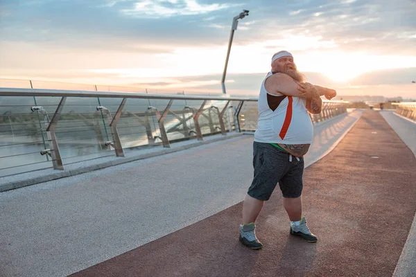 Fat caucasian bearded and bold man is doing morning exercses to loose his weight