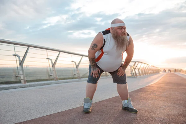 Şişman, beyaz sakallı ve cesur adam sabah egzersizleri yapıyor.