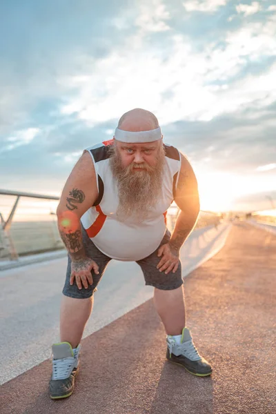 Şişman, beyaz sakallı ve cesur adam sabah egzersizleri yapıyor.