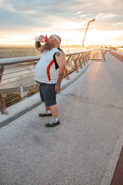 Fat caucasian bearded and bold man is doing morning exercses to loose his weight