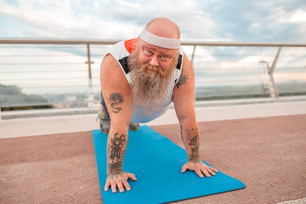 Fat caucasian bearded and bold man is doing morning exercses to loose his weight