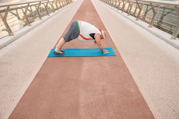 Fat caucasian bearded and bold man is doing morning exercses to loose his weight