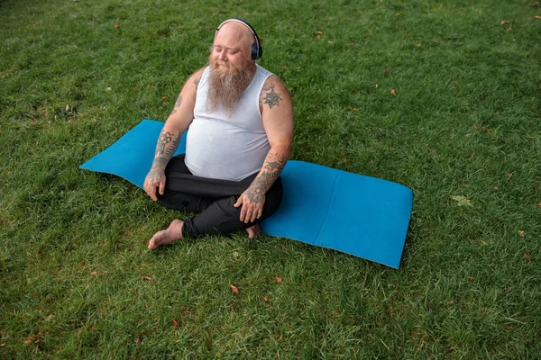 Şişman, beyaz sakallı ve cesur adam sabah egzersizleri yapıyor.