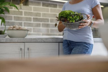 Güzel, hoş ve yakışıklı kadın evdeki mutfağında lezzetli, sağlıklı bir salata hazırlıyor.