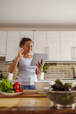 Güzel, hoş ve yakışıklı kadın evdeki mutfağında lezzetli, sağlıklı bir salata hazırlıyor.
