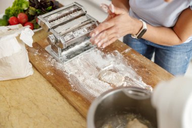 Güzel ve güzel bir kadın evdeki mutfağında taze çiğ İtalyan makarnası hazırlıyor.