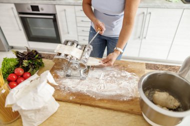 Güzel ve güzel bir kadın evdeki mutfağında taze çiğ İtalyan makarnası hazırlıyor.