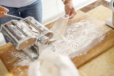 Güzel ve güzel bir kadın evdeki mutfağında taze çiğ İtalyan makarnası hazırlıyor.