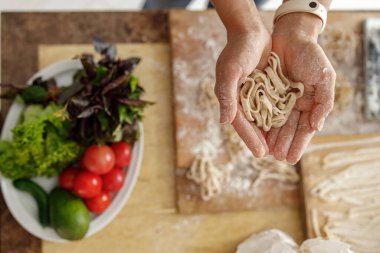 Güzel ve güzel bir kadın evdeki mutfağında taze çiğ İtalyan makarnası hazırlıyor.