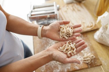 Güzel ve güzel bir kadın evdeki mutfağında taze çiğ İtalyan makarnası hazırlıyor.