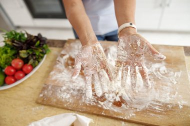 Güzel, hoş, yakışıklı bir kadın evdeki mutfağında sebzeli taze İtalyan pizzası hazırlıyor.