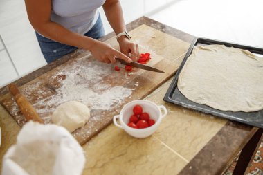 Güzel, hoş, yakışıklı bir kadın evdeki mutfağında sebzeli taze İtalyan pizzası hazırlıyor.