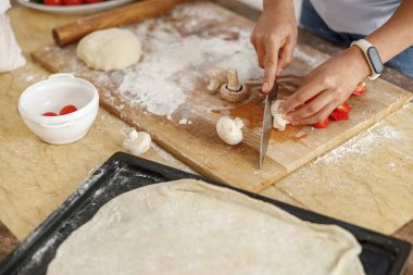 Güzel, hoş, yakışıklı bir kadın evdeki mutfağında sebzeli taze İtalyan pizzası hazırlıyor.
