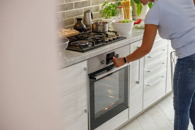 Güzel, hoş, yakışıklı bir kadın evdeki mutfağında sebzeli taze İtalyan pizzası hazırlıyor.