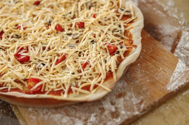 Güzel, hoş, yakışıklı bir kadın evdeki mutfağında sebzeli taze İtalyan pizzası hazırlıyor.