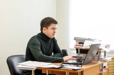 Sıradan bir iş adamı ofiste çalışır, masada oturur, klavyeye yazar, bilgisayar ekranına bakar. Ofis işi kavramı.