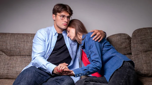 Una triste pareja está sentada en el sofá de su casa, copiando el espacio. Pelea, relación. Chica trastornada —  Fotos de Stock