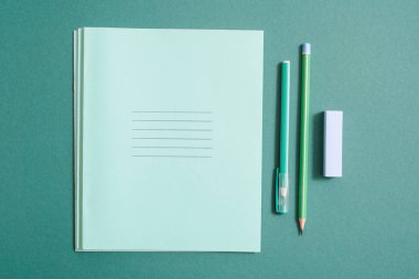 Okul malzemeleri, defter, kalem ve kurşun kalem yeşil bir arka plan üzerinde. kopya alanı