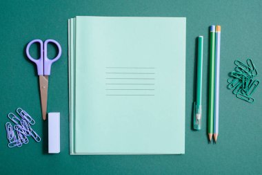 Okul malzemeleri, defter, kalem ve kurşun kalem yeşil bir arka plan üzerinde. kopya alanı