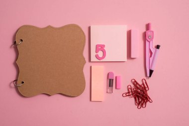 Boş defter sayfası renkli kalemler ile en iyi görünümü tablo. Düz yatıyordu. Okul malzemeleri, kalem, makas, silgi ve pembe bir arka plan üzerinde renkli kalemler.