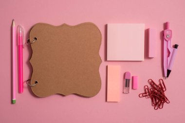 Boş defter sayfası renkli kalemler ile en iyi görünümü tablo. Düz yatıyordu. Okul malzemeleri, kalem, makas, silgi ve pembe bir arka plan üzerinde renkli kalemler.