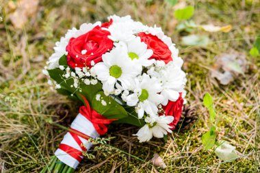 Ormanın içinde kırmızı beyaz buket düğün. Alyans renkler üzerinde.