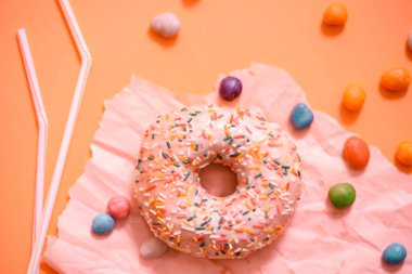 Serpilir pembe çörek. Pembe arka plan üzerine serpilir çörek buzlu. Tübüllerin bir kokteyl için. Kırık renkli şeker.