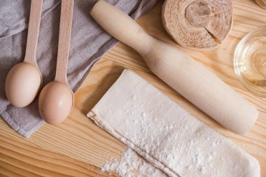 Hamur hazırlama. Malzemeler hamur - yumurta ve un bir oklava ile için. Ahşap arka plan üzerinde. Üstten görünüm