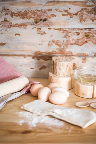 Preparation of the dough. Ingredients for the dough - Eggs and flour with a rolling pin. On wooden background. Free space for text .